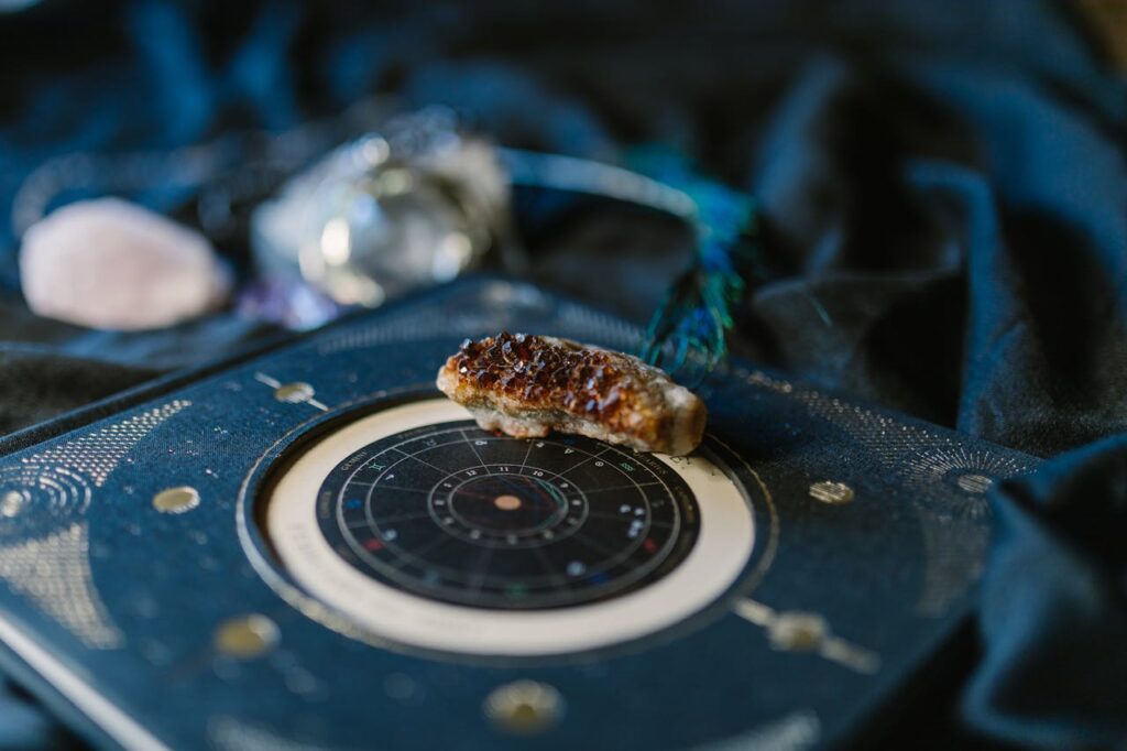 Close-up of crystals on an astrology chart atop dark fabric for a mystical vibe.
